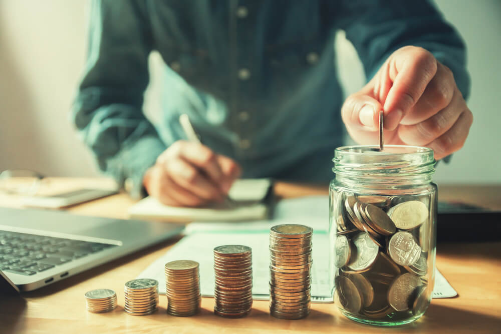 Businessman Putting Coins Into Jug Glass