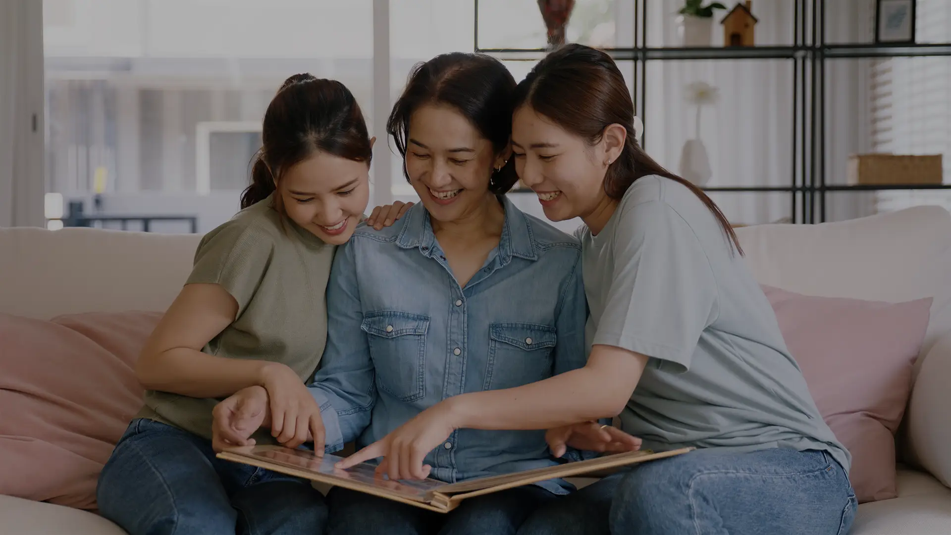 three women smiling while looking at a photo memory book